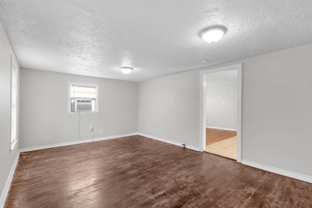 spare room with hardwood / wood-style floors, a textured ceiling, and cooling unit