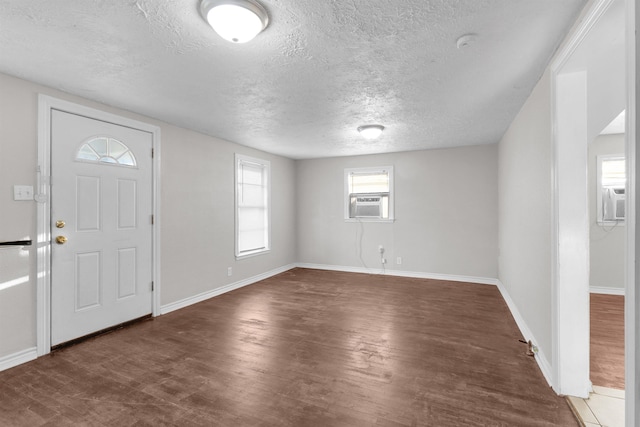 foyer with a textured ceiling, cooling unit, and dark wood-type flooring