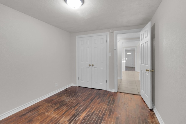 unfurnished bedroom with a textured ceiling, dark wood-type flooring, and a closet