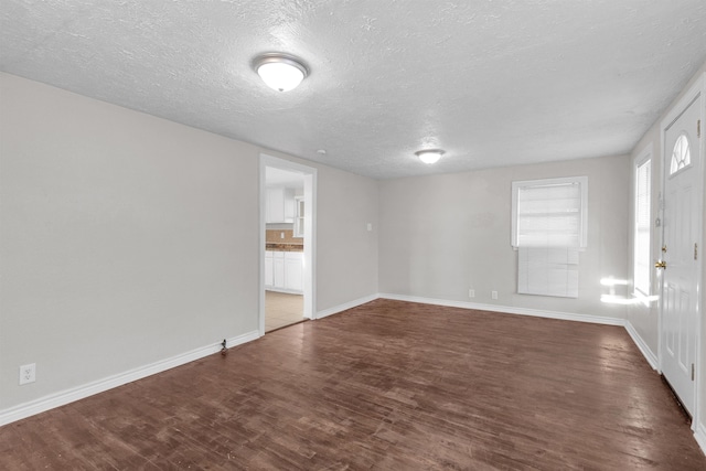 unfurnished room featuring dark hardwood / wood-style flooring and a textured ceiling