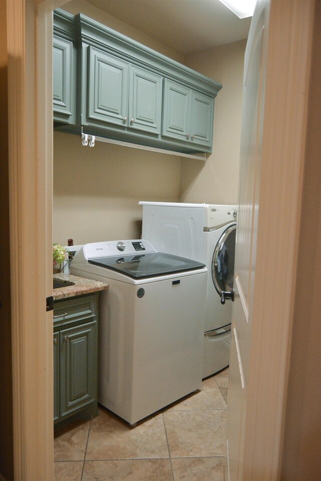 laundry area with light tile patterned flooring, cabinet space, and separate washer and dryer