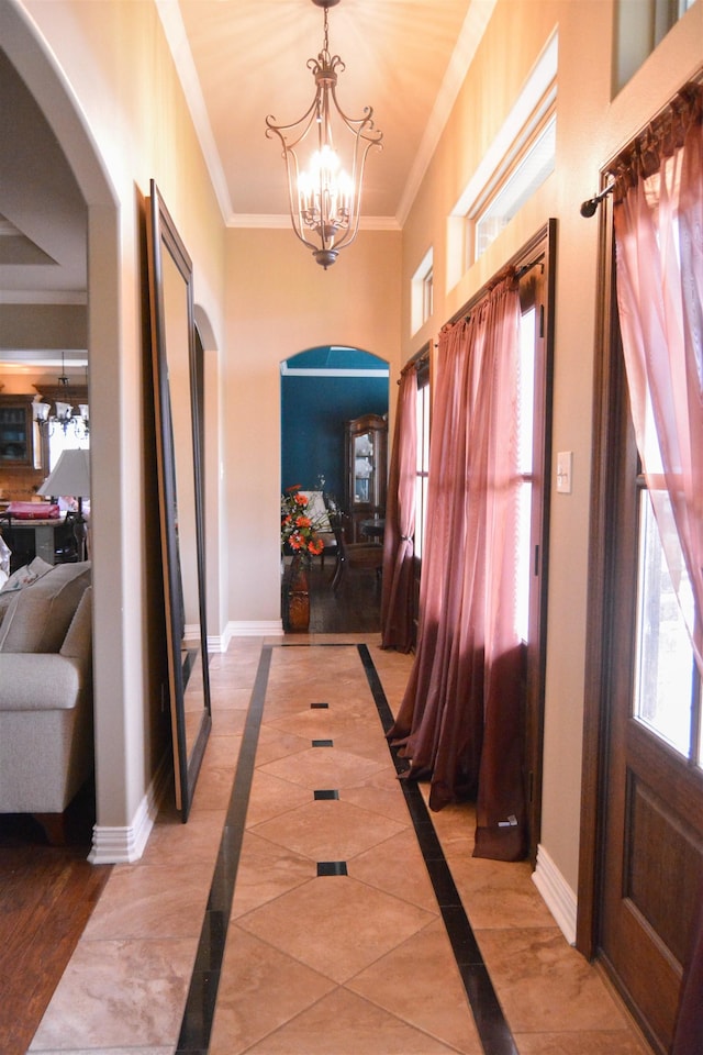 entryway featuring plenty of natural light, arched walkways, baseboards, and ornamental molding