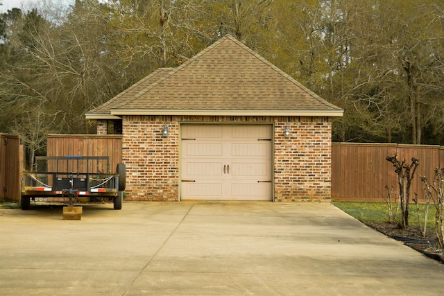 garage with concrete driveway and fence