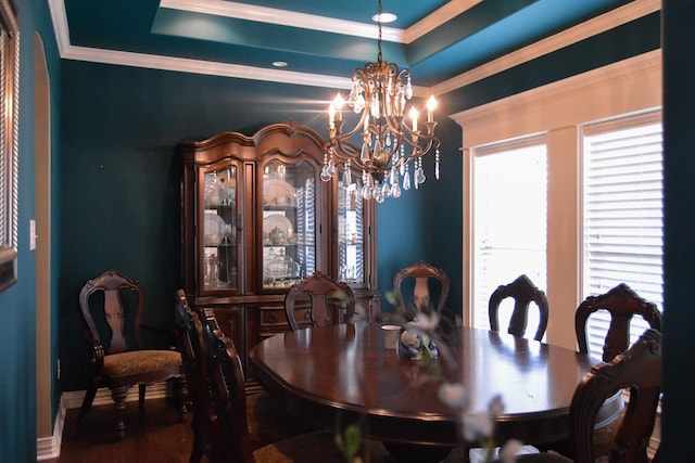 dining room with a tray ceiling, a notable chandelier, and crown molding