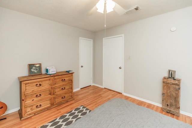 bedroom with baseboards, light wood-style flooring, visible vents, and a ceiling fan