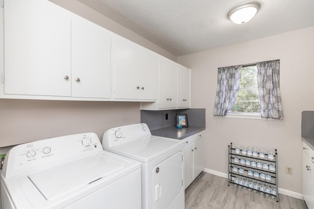 laundry area with washing machine and clothes dryer, cabinet space, baseboards, and light wood finished floors