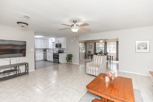 living room with a ceiling fan, light tile patterned floors, baseboards, and visible vents