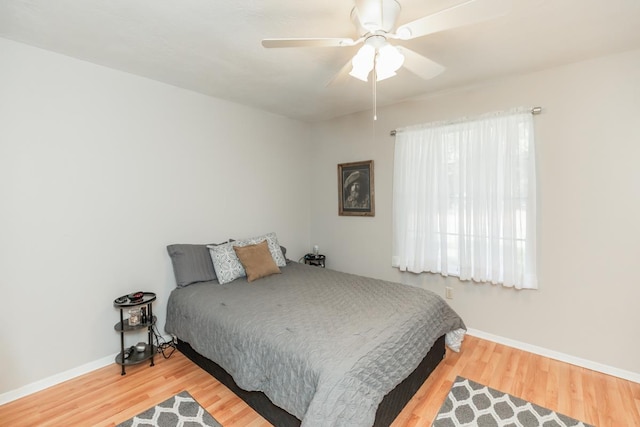 bedroom featuring baseboards, wood finished floors, and a ceiling fan