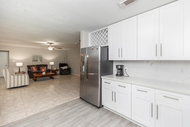 kitchen with stainless steel fridge with ice dispenser, white cabinets, visible vents, and light countertops