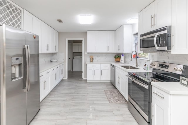 kitchen featuring decorative backsplash, visible vents, stainless steel appliances, a sink, and washer / dryer