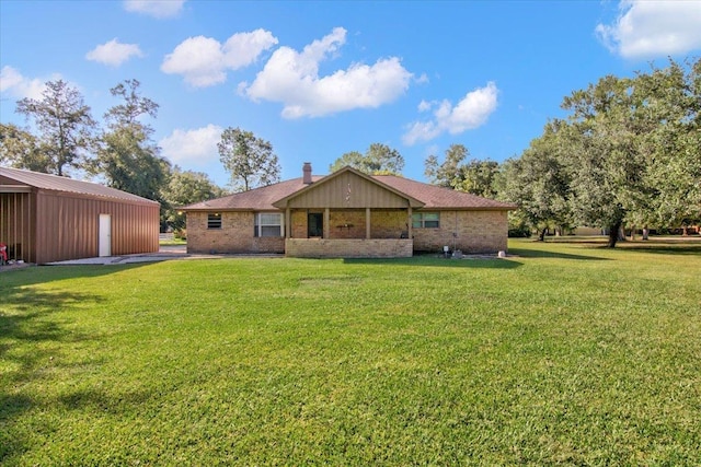 rear view of house featuring a lawn and an outdoor structure