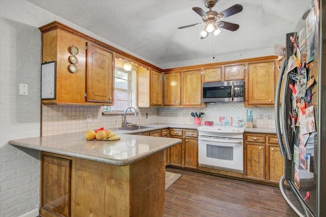 kitchen featuring kitchen peninsula, appliances with stainless steel finishes, backsplash, ceiling fan, and sink