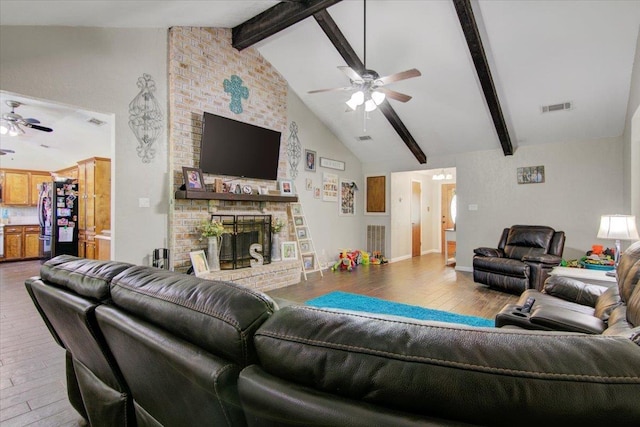 living room featuring ceiling fan, a fireplace, and lofted ceiling with beams