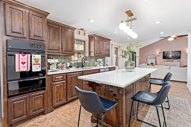 kitchen featuring a kitchen bar, sink, tasteful backsplash, a center island, and hanging light fixtures