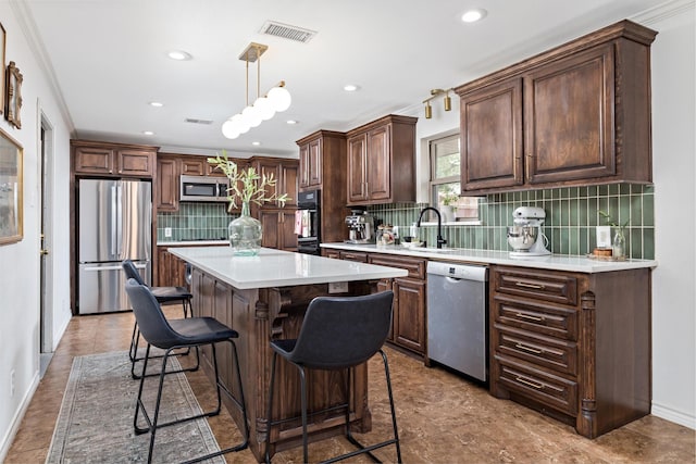 kitchen with sink, hanging light fixtures, a kitchen island, stainless steel appliances, and decorative backsplash