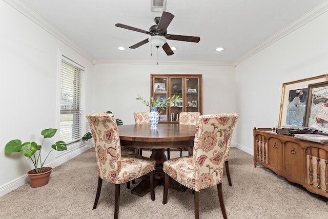 dining room featuring ornamental molding, light colored carpet, and ceiling fan