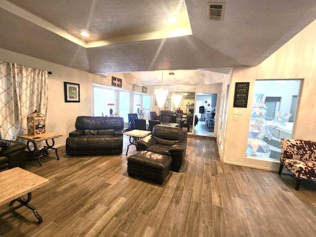 living room with wood-type flooring, a textured ceiling, and a tray ceiling