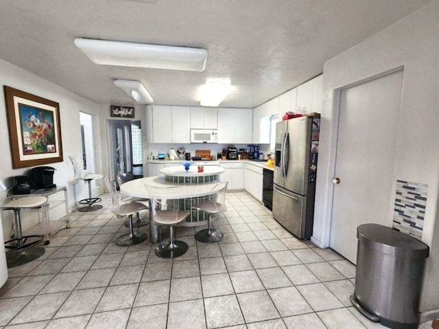 kitchen featuring white cabinetry, stainless steel fridge with ice dispenser, light tile patterned floors, and a textured ceiling