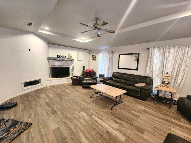 living room featuring a tray ceiling, ceiling fan, and wood-type flooring