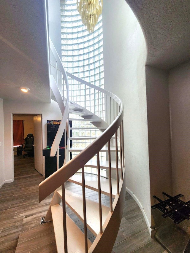 stairs featuring hardwood / wood-style flooring and an inviting chandelier