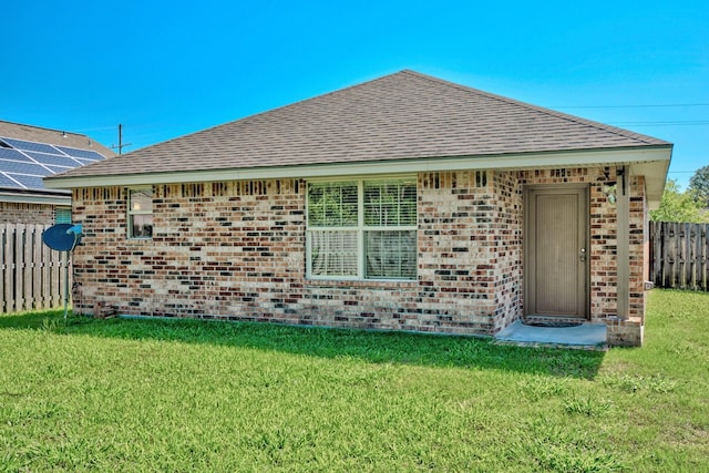 6640 Palace Dr, Lumberton, TX 77657 - back of house with roof with shingles, a lawn, fence, and brick siding