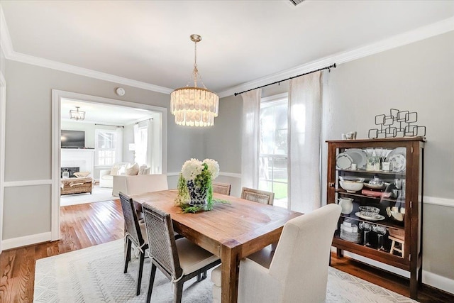 dining area featuring hardwood / wood-style flooring, ornamental molding, and an inviting chandelier