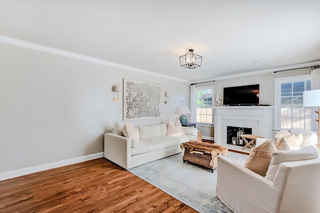 living room featuring hardwood / wood-style flooring, ornamental molding, a high end fireplace, and an inviting chandelier