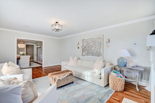 living room featuring hardwood / wood-style flooring, a notable chandelier, and crown molding