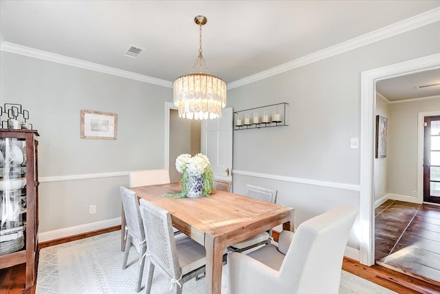 dining room with a notable chandelier, light wood-type flooring, and ornamental molding