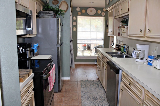 kitchen featuring cream cabinetry, appliances with stainless steel finishes, light tile patterned floors, and sink