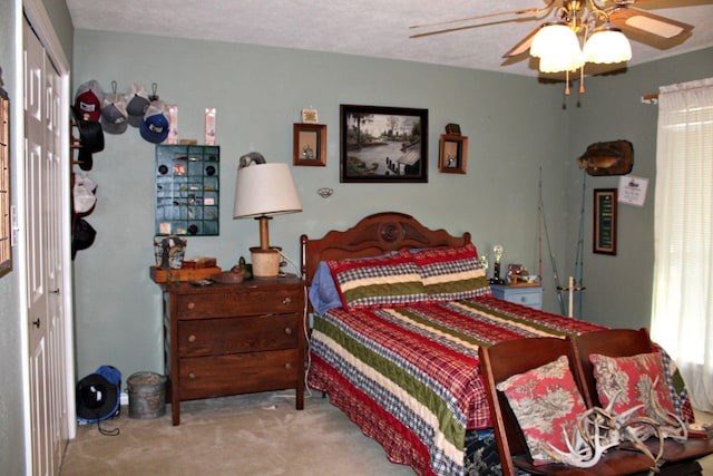 bedroom with ceiling fan, light colored carpet, a textured ceiling, and a closet