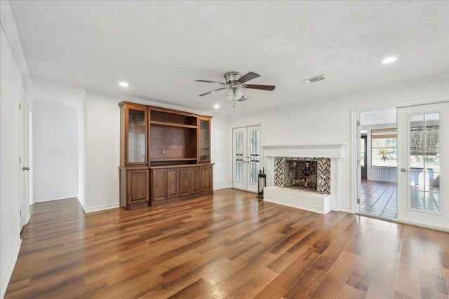 345 Mayhaw Dr, Vidor, TX 77662 - unfurnished living room with a textured ceiling, visible vents, a brick fireplace, ceiling fan, and wood finished floors