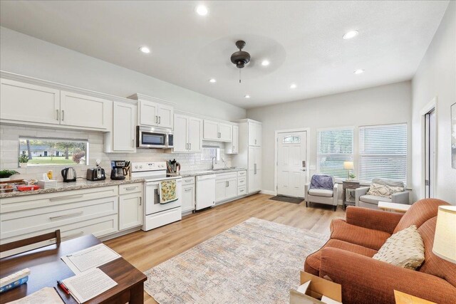 345 Mayhaw Dr, Vidor, TX 77662 - kitchen featuring light wood finished floors, white appliances, a sink, open floor plan, and backsplash