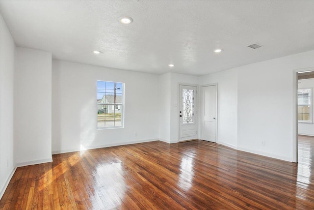 spare room with dark hardwood / wood-style flooring, plenty of natural light, and a textured ceiling