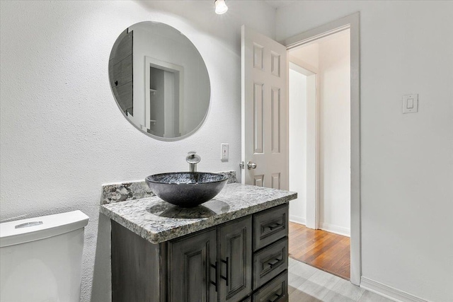 bathroom with toilet, wood-type flooring, and vanity