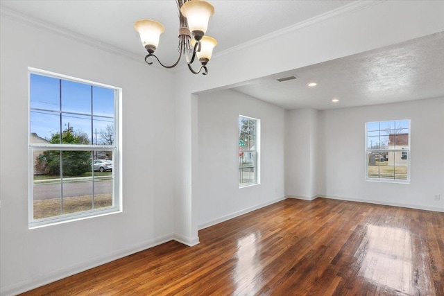 spare room featuring dark wood-type flooring, a textured ceiling, crown molding, and an inviting chandelier