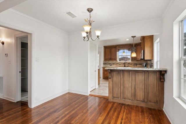 kitchen featuring kitchen peninsula, decorative backsplash, decorative light fixtures, a notable chandelier, and dark wood-type flooring