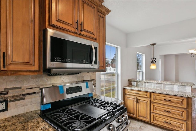 kitchen with an inviting chandelier, stainless steel appliances, tasteful backsplash, and light stone counters