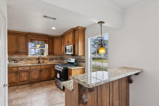 kitchen featuring appliances with stainless steel finishes, a kitchen breakfast bar, hanging light fixtures, sink, and kitchen peninsula