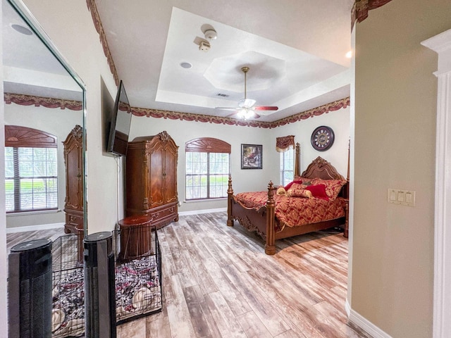 2460 W Norman Cir, Orange, TX 77630 - bedroom with baseboards, a tray ceiling, multiple windows, and light wood-style floors