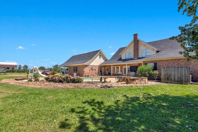 7230 W Fm 1004, Buna, TX 77612 - rear view of house with a patio area, a yard, brick siding, and a chimney