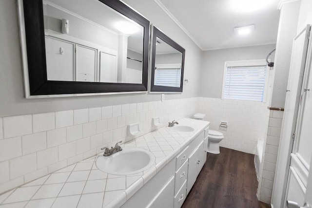 bathroom with tile walls, hardwood / wood-style floors, toilet, vanity, and ornamental molding