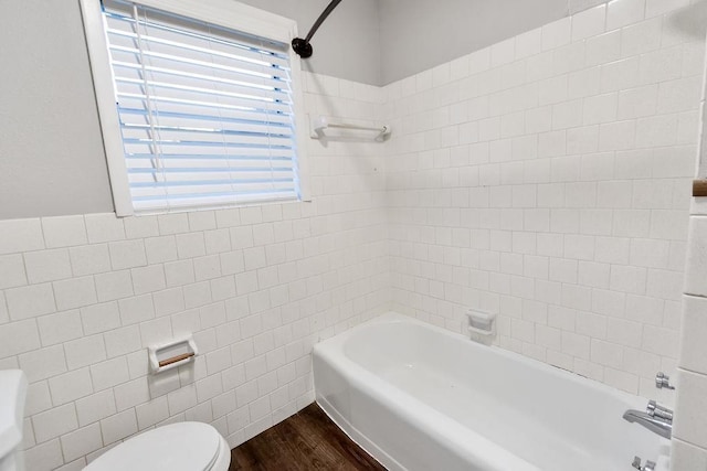 bathroom with toilet, tile walls, tiled shower / bath combo, and wood-type flooring