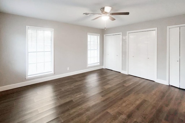 unfurnished bedroom featuring multiple closets, ceiling fan, and dark hardwood / wood-style flooring