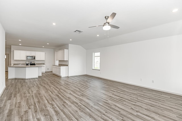 unfurnished living room featuring ceiling fan, vaulted ceiling, and light hardwood / wood-style flooring