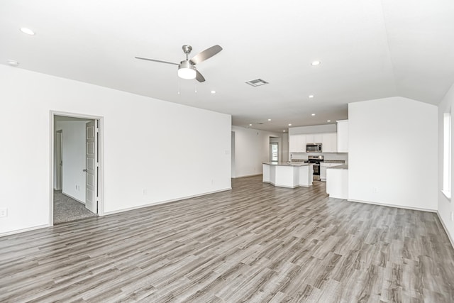 unfurnished living room featuring light hardwood / wood-style floors, vaulted ceiling, and ceiling fan