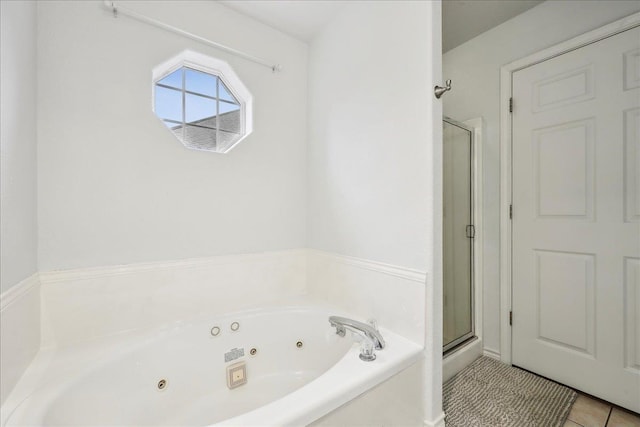 bathroom featuring tile patterned flooring, a shower stall, and a tub with jets