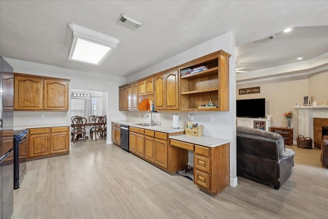 kitchen featuring dishwashing machine, black range with electric cooktop, visible vents, built in desk, and brown cabinetry