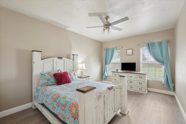 bedroom featuring light wood-type flooring, a textured ceiling, and baseboards