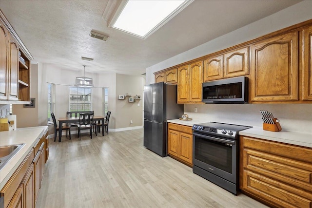 kitchen featuring stainless steel appliances, light wood-type flooring, light countertops, and brown cabinets